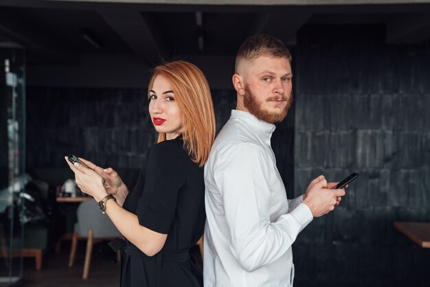 La pareja se pone de espaldas con los teléfonos inteligentes en las manos.