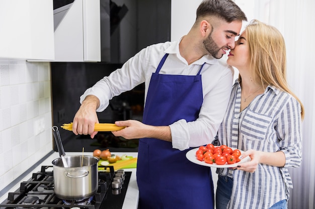 Pareja poniendo espaguetis en una olla con agua hervida