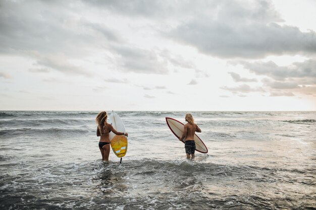 Pareja posa en la playa y va a surfear