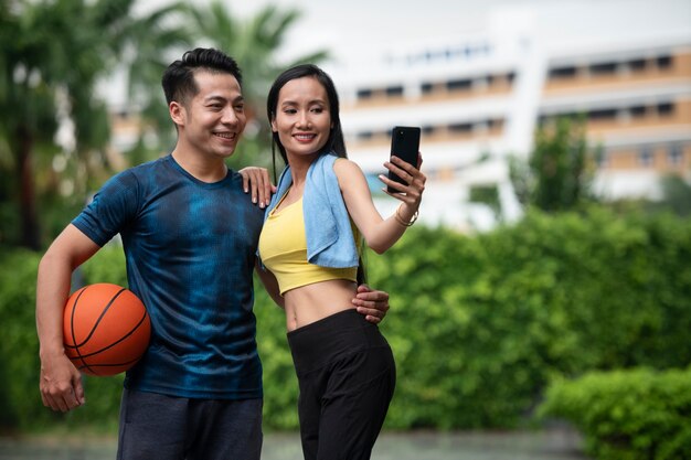 Pareja posando juntos al aire libre para un selfie con baloncesto