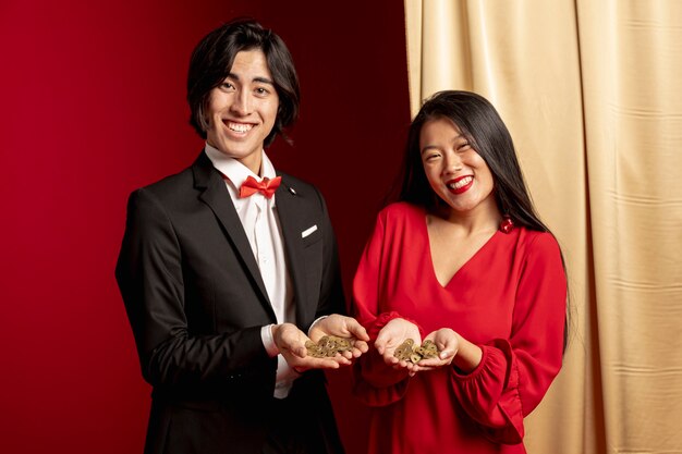 Pareja posando mientras sostiene monedas chinas de oro para año nuevo