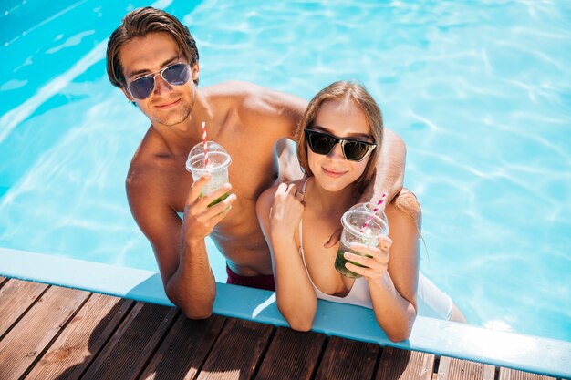 Pareja posando y mirando a la cámara en la piscina