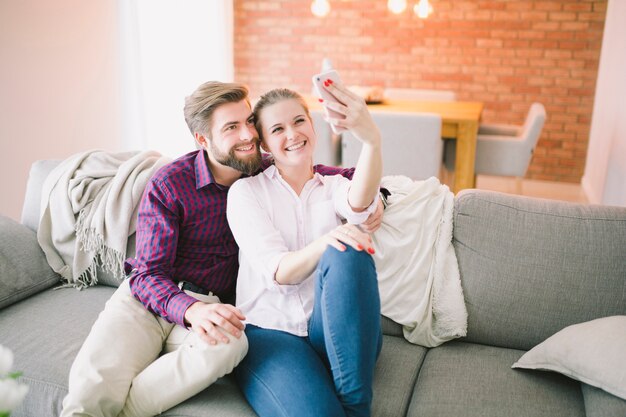 Pareja posando para selfie en el sofá