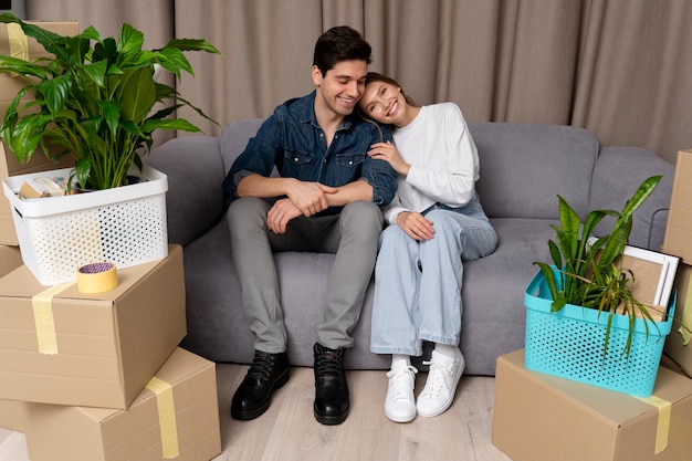 Pareja posando sentada en el sofá de su nueva casa