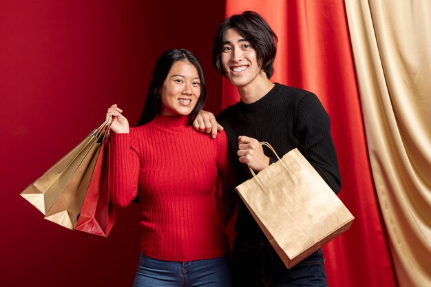 Pareja posando y sosteniendo bolsas de papel para el año nuevo chino