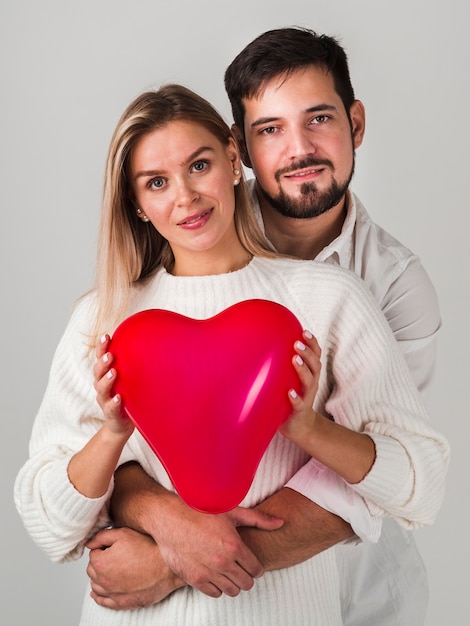 Pareja posando y sosteniendo el globo y sonriendo