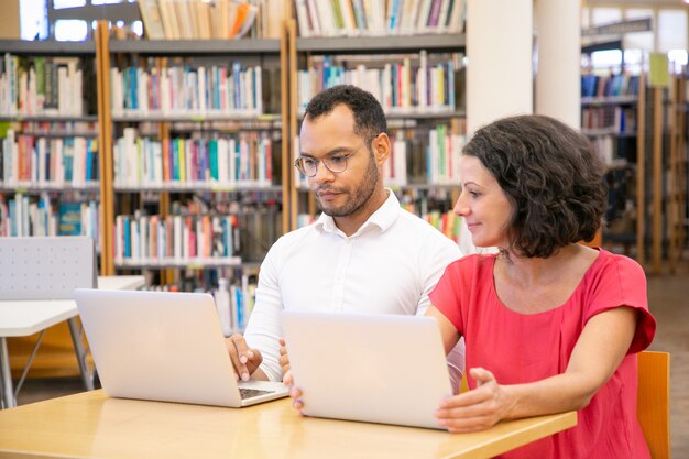 Pareja positiva de estudiantes adultos haciendo y discutiendo investigaciones