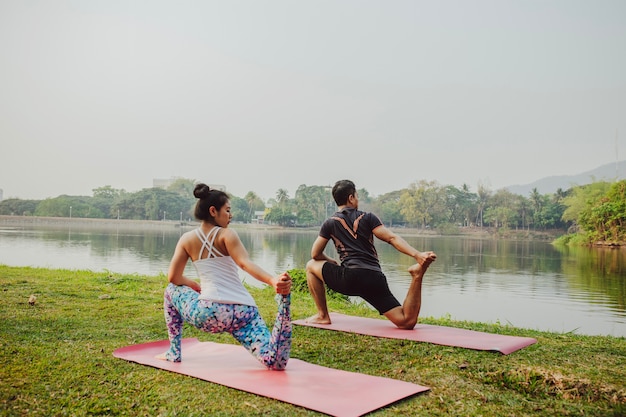 Foto gratuita pareja practicando yoga junto al lago