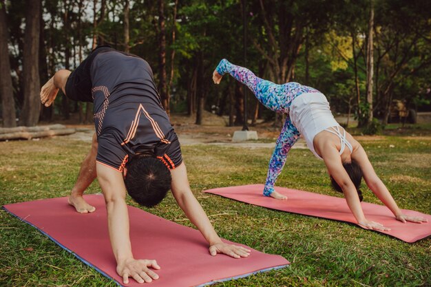 Pareja practicando yoga en el parque