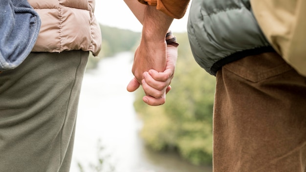 Pareja de primer plano cogidos de la mano cerca del río