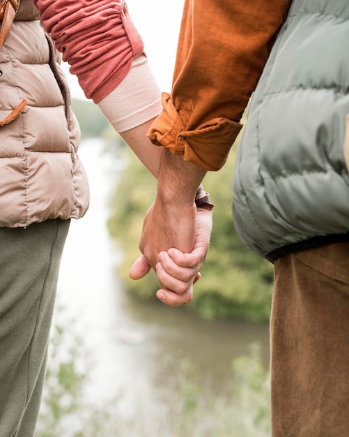 Foto gratuita pareja de primer plano cogidos de la mano cerca del río