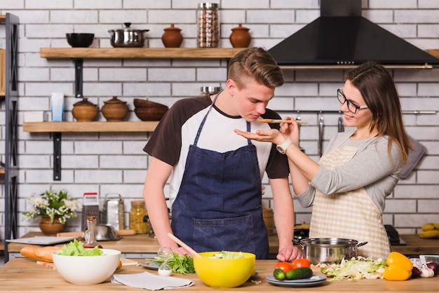 Pareja probando comida mientras cocinan juntos