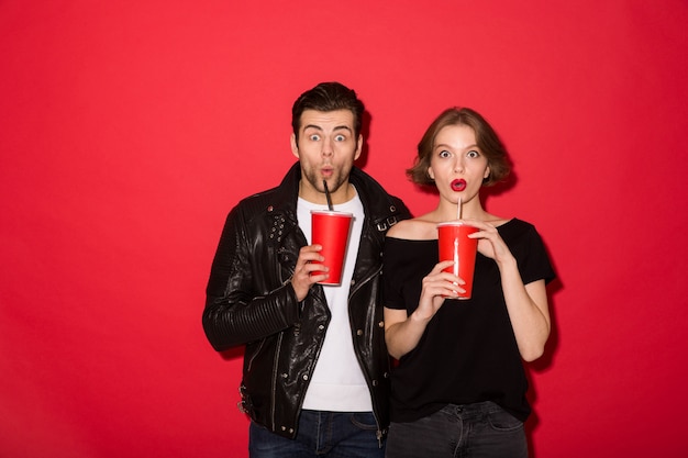 Pareja punk sorprendida bebiendo refrescos y mirando