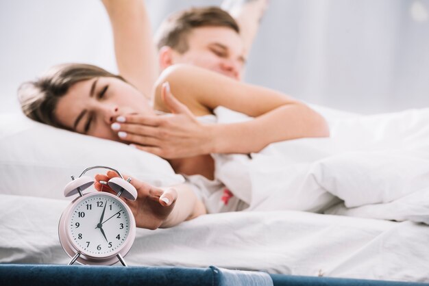 Pareja que se despierta cerca del despertador con 5am