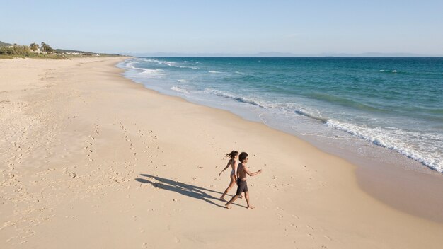 Pareja que va a las olas de espuma a lo largo de la costa