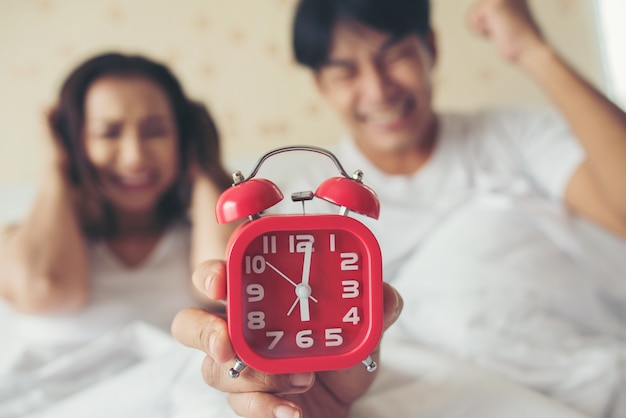 Pareja que tiene problemas para levantarse temprano en la mañana en la cama