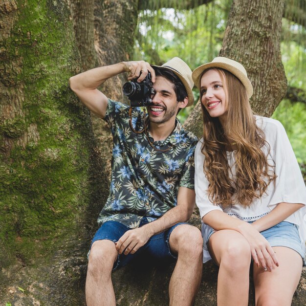 Pareja en raíz de árbol con camera