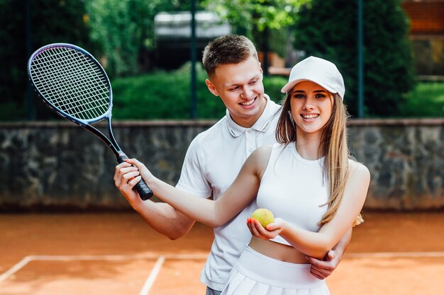 Pareja con raquetas de tenis en cancha al aire libre