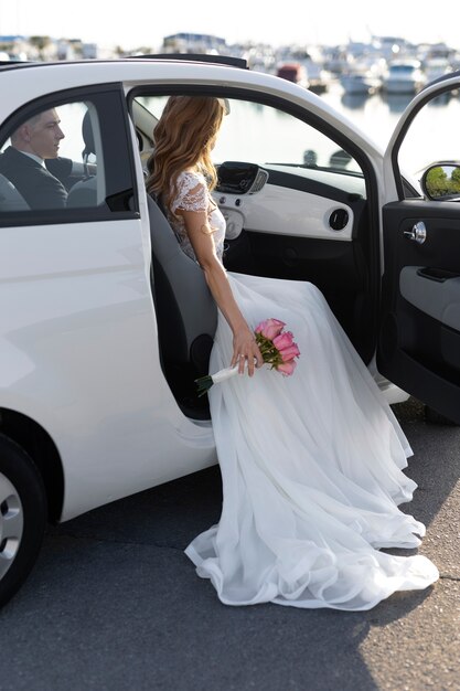 Una pareja recién casada se sienta dentro de un auto pequeño