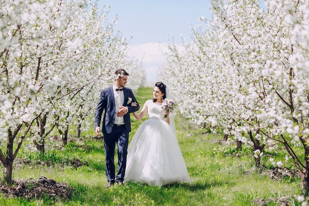 Pareja de recién casados caminando entre los árboles en flor