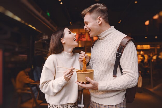 Pareja de recién casados comiendo fideos con palillos en Shanghai fuera de un mercado de alimentos