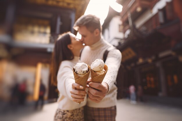 Pareja de recién casados comiendo helado de un cono en una calle de Shanghai, cerca de Yuyuan, China.