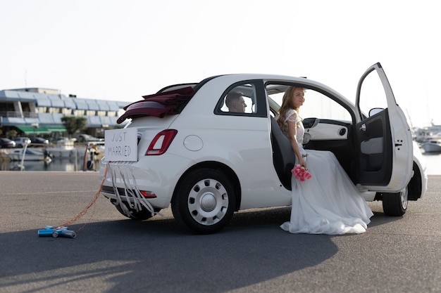 Una pareja de recién casados dentro de un auto pequeño