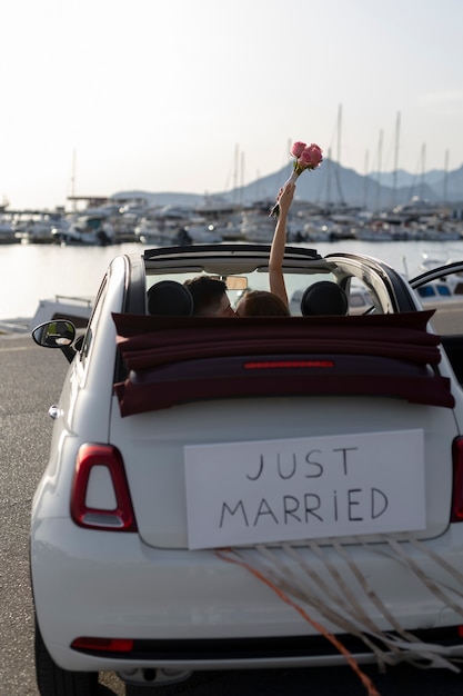 Una pareja de recién casados dentro de un auto pequeño