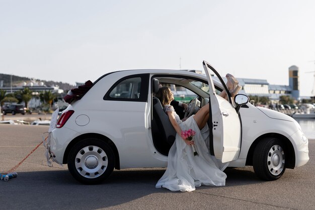 Una pareja de recién casados dentro de un auto pequeño