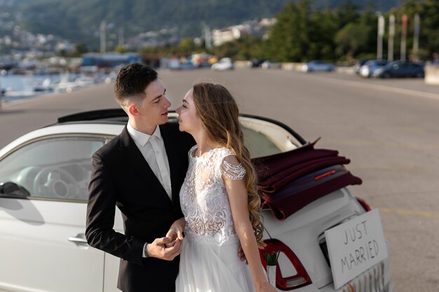 Una pareja de recién casados junto a un auto pequeño