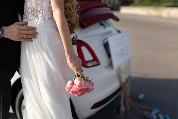 Foto gratuita una pareja de recién casados junto a un auto pequeño