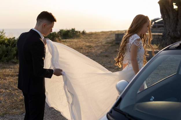 Una pareja de recién casados junto a un auto pequeño