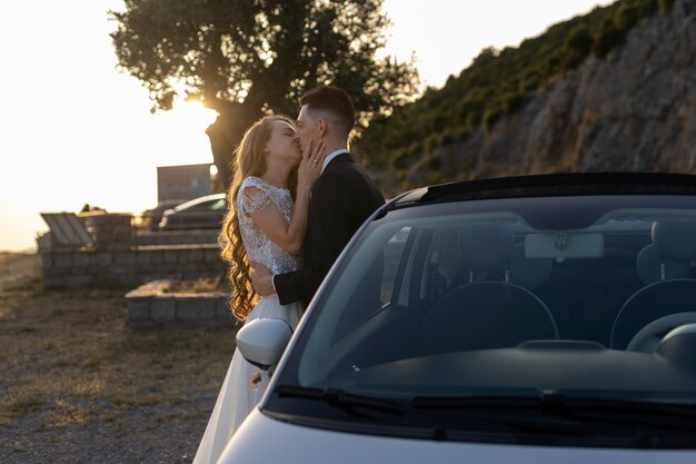 Una pareja de recién casados junto a un auto pequeño