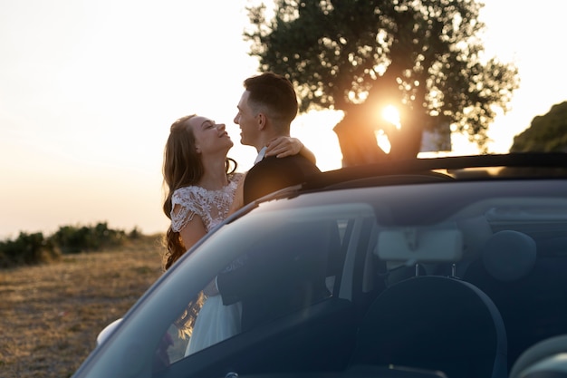 Una pareja de recién casados junto a un auto pequeño