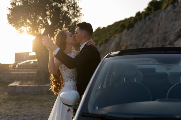 Una pareja de recién casados junto a un auto pequeño