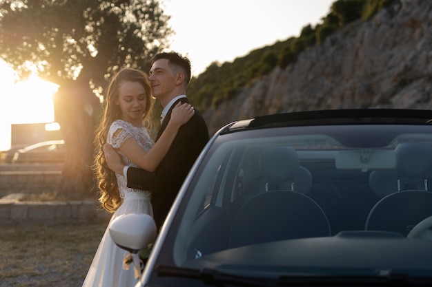 Foto gratuita una pareja de recién casados junto a un auto pequeño