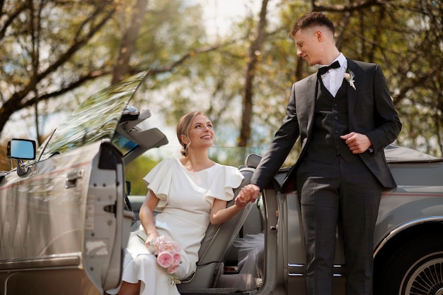 Foto gratuita pareja de recién casados con su coche