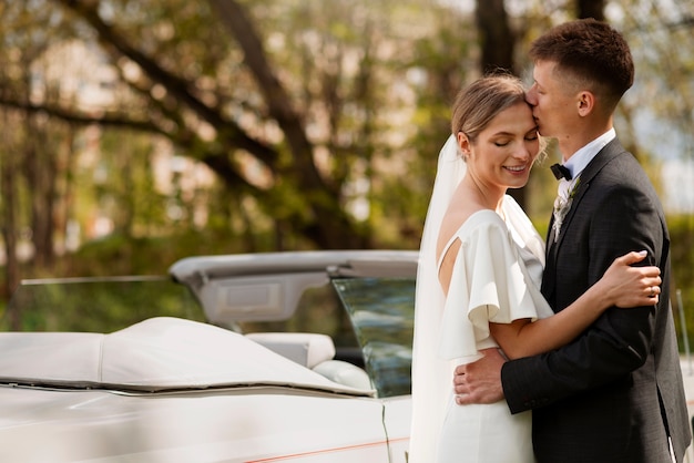 Pareja de recién casados con su coche