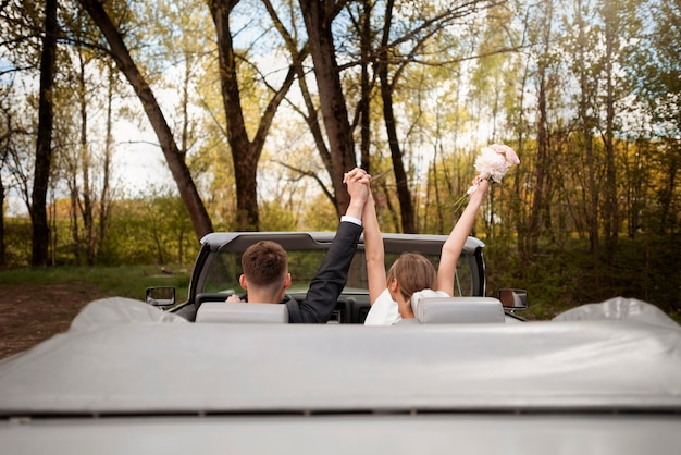 Pareja de recién casados con su coche