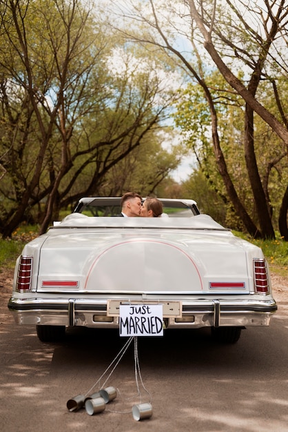 Pareja de recién casados con su coche