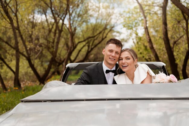 Pareja de recién casados con su coche