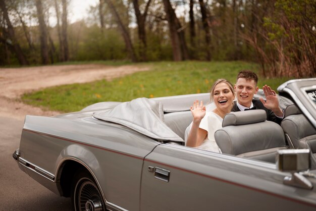 Pareja de recién casados con su coche