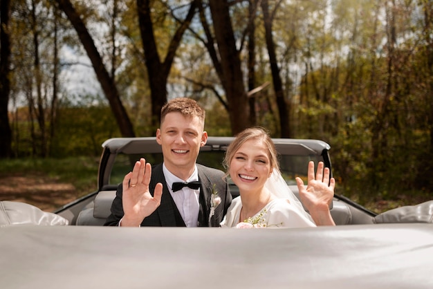 Pareja de recién casados con su coche