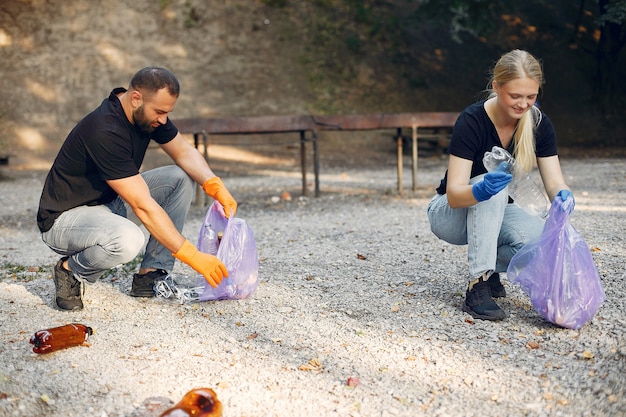 Pareja recoge basura en bolsas de basura en el parque