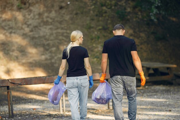 Pareja recoge basura en bolsas de basura en el parque