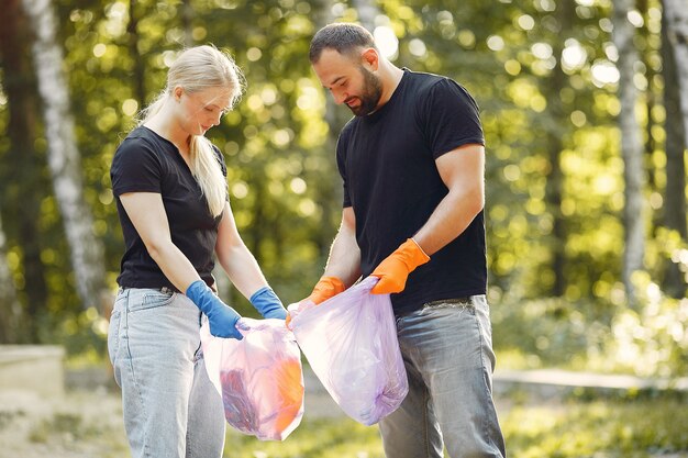 Pareja recoge basura en bolsas de basura en el parque