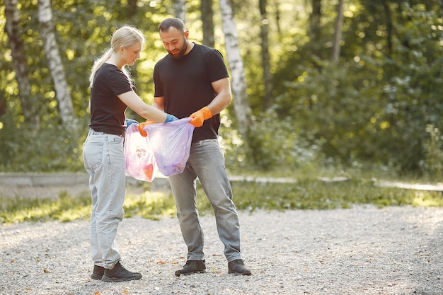 Pareja recoge basura en bolsas de basura en el parque