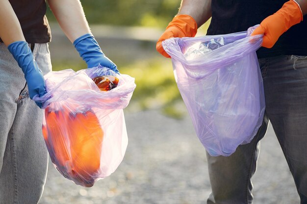 Pareja recoge basura en bolsas de basura en el parque