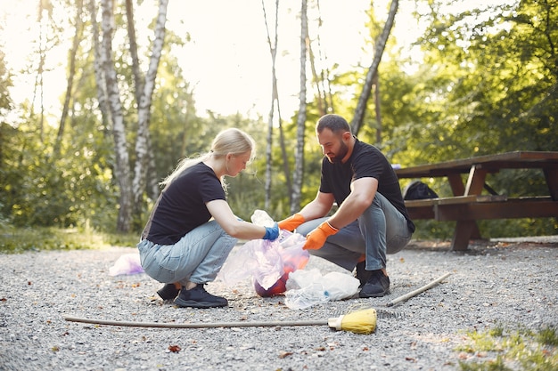 Foto gratuita pareja recoge basura en bolsas de basura en el parque