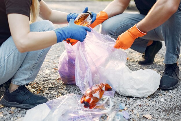 Pareja recoge basura en bolsas de basura en el parque